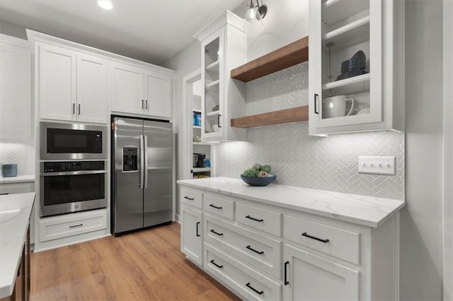 1717 SW Arbormill Ter, Lees Summit, MO 64082 - kitchen featuring appliances with stainless steel finishes, white cabinetry, decorative backsplash, open shelves, and light wood-type flooring