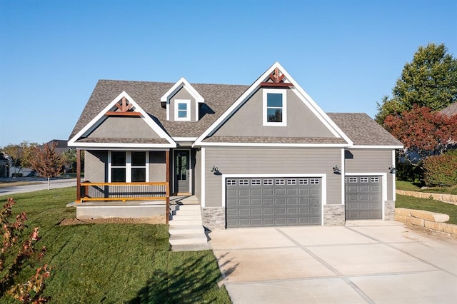 view of front of house featuring covered porch, a front yard, and a garage