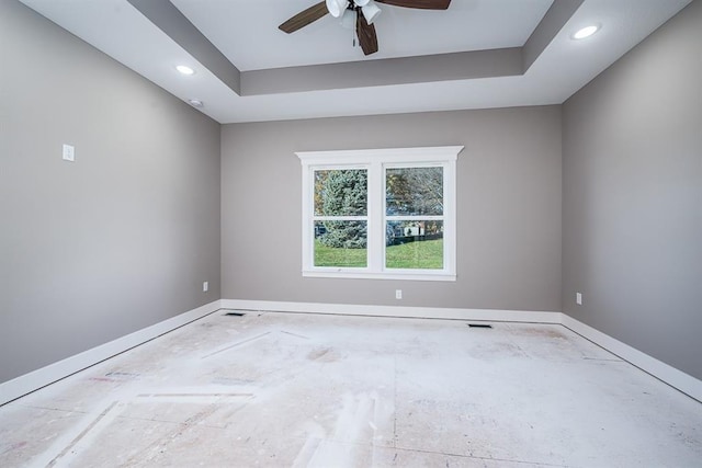 empty room with a raised ceiling and ceiling fan