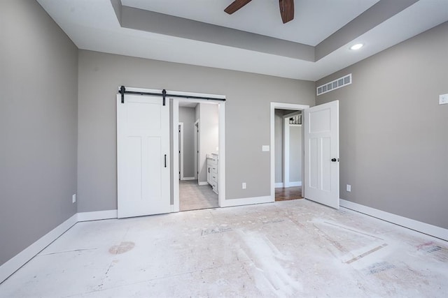 unfurnished bedroom featuring connected bathroom, a barn door, and ceiling fan