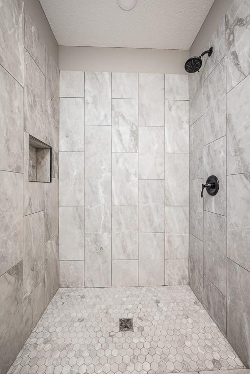 bathroom with tiled shower and a textured ceiling