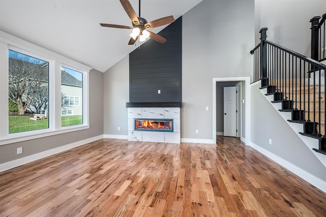 unfurnished living room with ceiling fan, a fireplace, high vaulted ceiling, and hardwood / wood-style floors