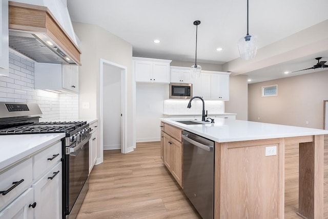 kitchen featuring premium range hood, a center island with sink, sink, appliances with stainless steel finishes, and white cabinetry