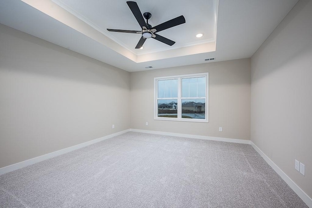 spare room with carpet floors, a tray ceiling, and ceiling fan