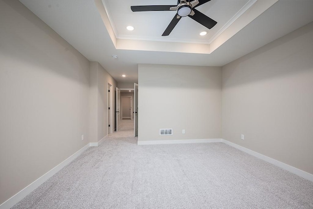 carpeted spare room with ceiling fan, a raised ceiling, and crown molding