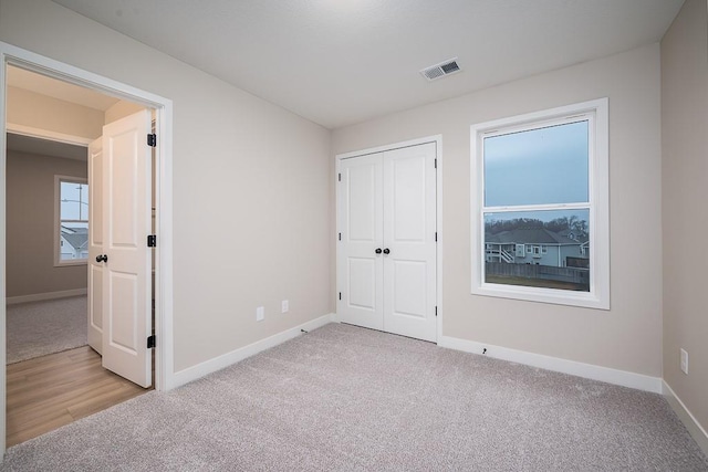 unfurnished bedroom with light colored carpet and a closet