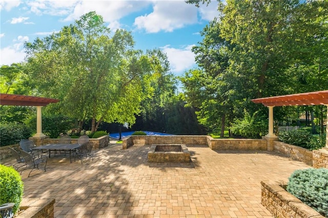 view of patio / terrace with outdoor dining area, a fire pit, and a pergola