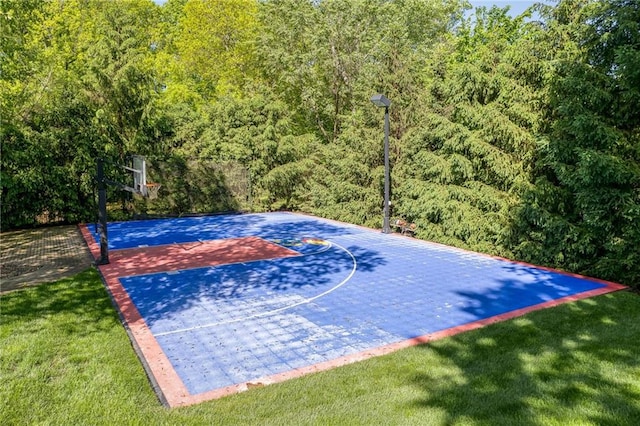 view of basketball court with a yard and basketball hoop