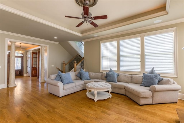 living room with stairs, a wealth of natural light, light wood-style flooring, and ornate columns