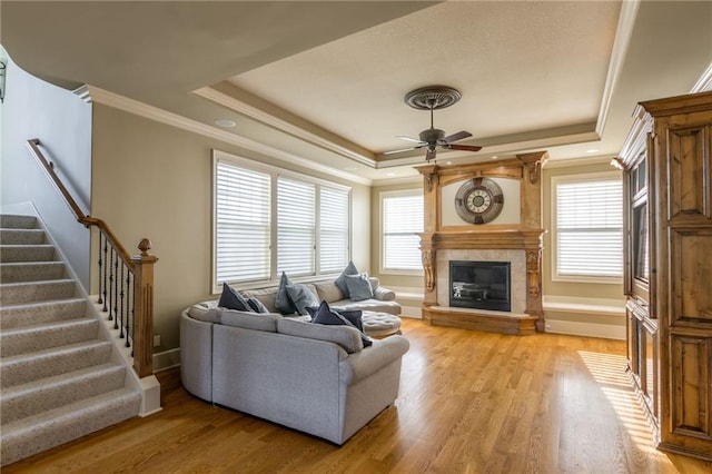 living room with a tray ceiling, a healthy amount of sunlight, and light wood-style floors