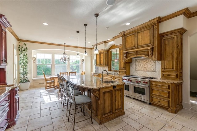 kitchen with range with two ovens, brown cabinetry, a sink, and tasteful backsplash