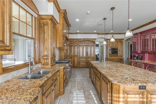 kitchen with stone tile floors, a spacious island, appliances with stainless steel finishes, ornamental molding, and a sink