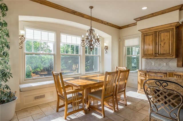 dining space featuring an inviting chandelier, stone tile flooring, visible vents, and crown molding