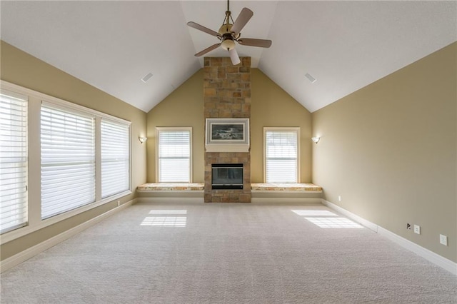 unfurnished living room with a wealth of natural light, visible vents, a stone fireplace, and carpet