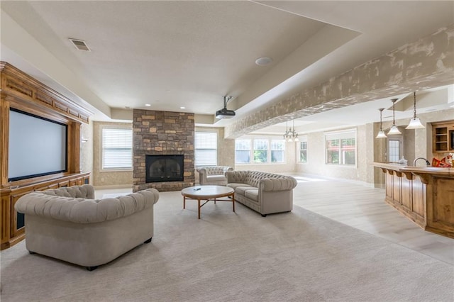 living room featuring light wood finished floors, a fireplace, visible vents, and a notable chandelier