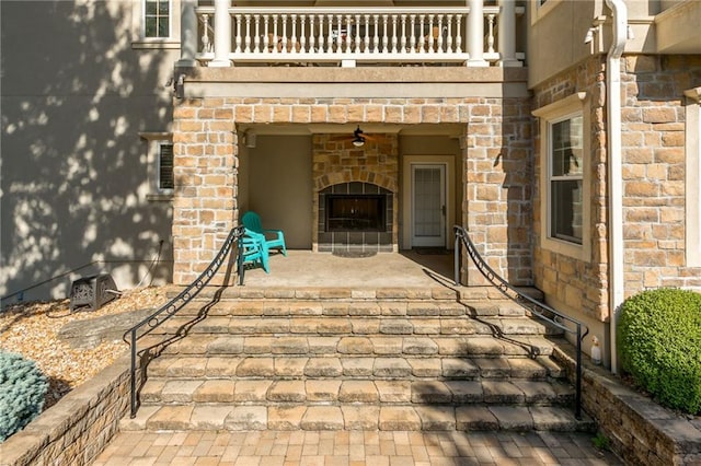 view of patio with a fireplace and a balcony