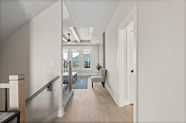 corridor with beamed ceiling and light hardwood / wood-style flooring