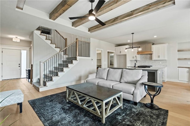 living room featuring ceiling fan, sink, beam ceiling, and light hardwood / wood-style floors