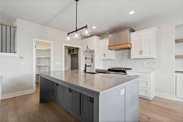 kitchen with a large island, white cabinets, light hardwood / wood-style floors, and pendant lighting