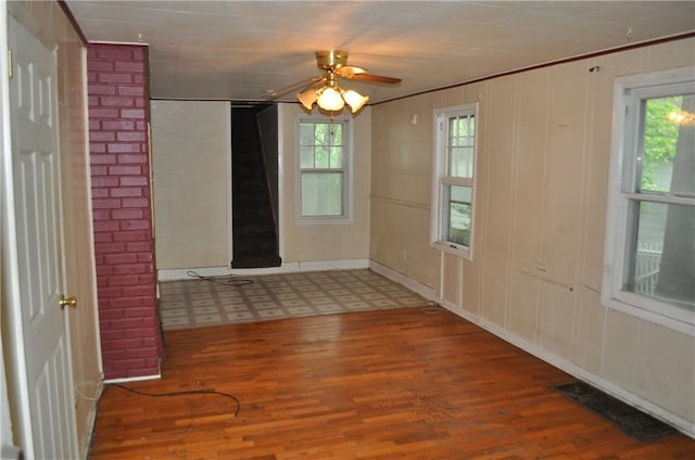 tiled spare room featuring a wealth of natural light, brick wall, and ceiling fan