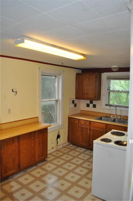 kitchen with sink, white electric stove, light tile floors, and backsplash