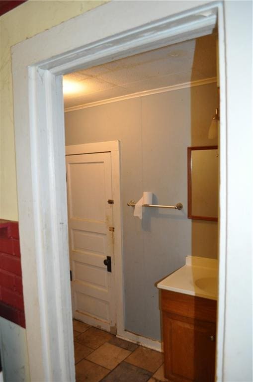 bathroom with tile flooring, ornamental molding, and vanity