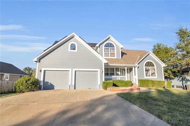 view of front of home with a garage, a front yard, and covered porch