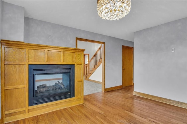 unfurnished living room featuring light hardwood / wood-style floors, a chandelier, and a multi sided fireplace