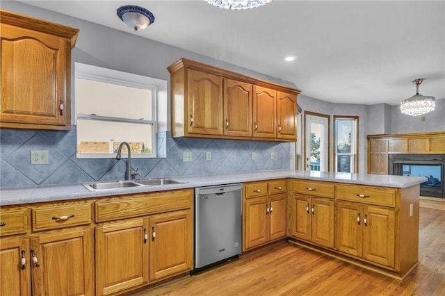 kitchen featuring sink, light hardwood / wood-style flooring, hanging light fixtures, and dishwasher