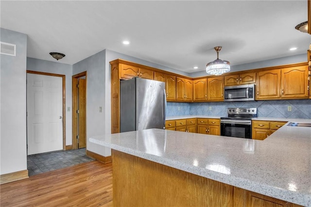 kitchen with stainless steel appliances, tasteful backsplash, hanging light fixtures, and kitchen peninsula