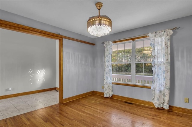 unfurnished room featuring light hardwood / wood-style floors and a notable chandelier