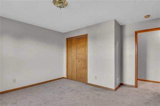 unfurnished bedroom with light carpet and a closet