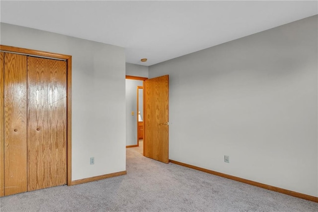 unfurnished bedroom featuring light colored carpet and a closet