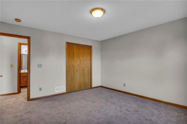 unfurnished bedroom featuring light colored carpet and a closet