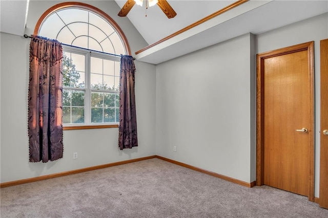 carpeted spare room with ceiling fan and vaulted ceiling