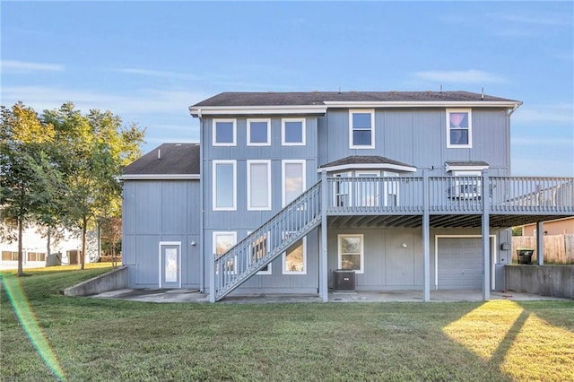 rear view of house featuring cooling unit, a wooden deck, a garage, and a yard