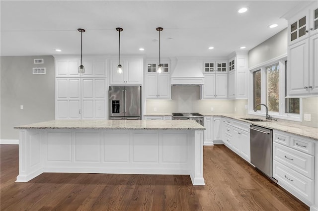 kitchen featuring white cabinets, a kitchen island, premium range hood, and appliances with stainless steel finishes