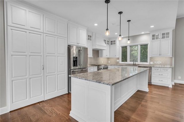 kitchen featuring custom exhaust hood, a center island, sink, appliances with stainless steel finishes, and white cabinetry