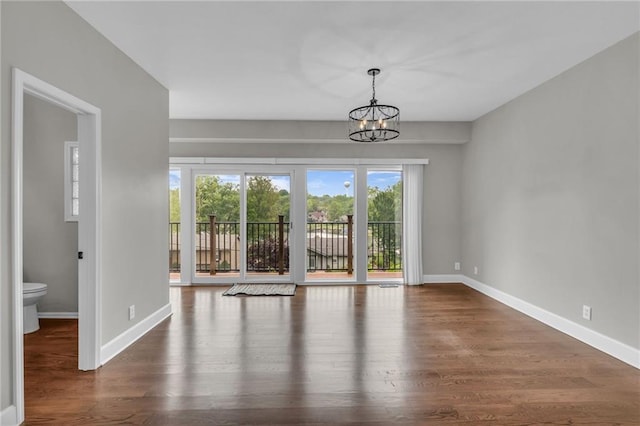 unfurnished room with dark hardwood / wood-style floors and an inviting chandelier