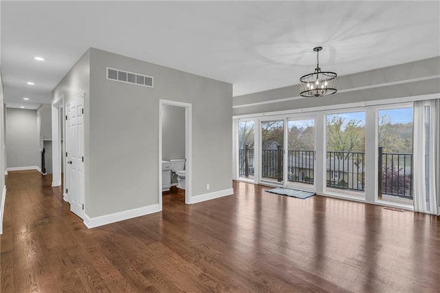 unfurnished living room featuring dark hardwood / wood-style flooring, a wealth of natural light, and an inviting chandelier