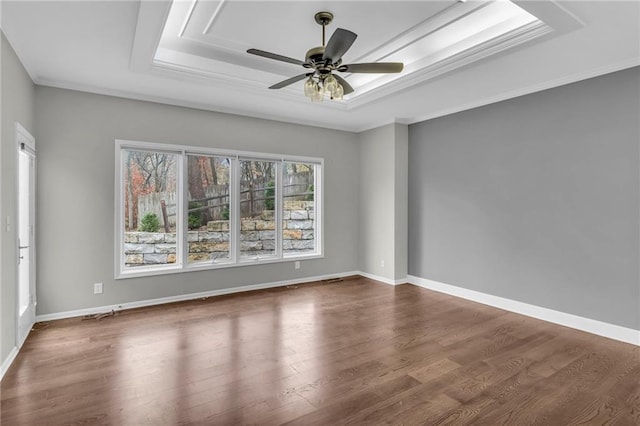 empty room with hardwood / wood-style flooring, ceiling fan, and a tray ceiling