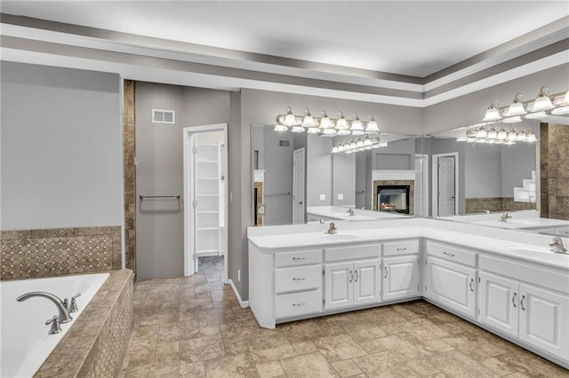 bathroom featuring tiled bath, a fireplace, and vanity