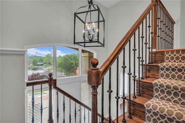 staircase featuring hardwood / wood-style floors, a water view, and an inviting chandelier