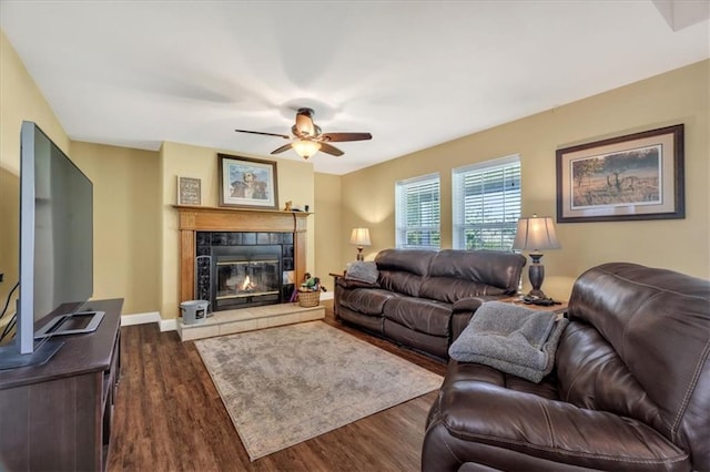 living room featuring dark hardwood / wood-style floors, ceiling fan, and a tiled fireplace