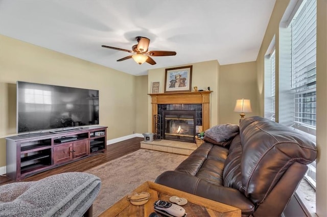 living room with ceiling fan, dark wood-type flooring, and a tile fireplace