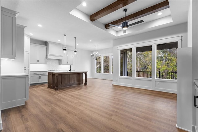 kitchen featuring hanging light fixtures, hardwood / wood-style flooring, a center island with sink, and ceiling fan with notable chandelier