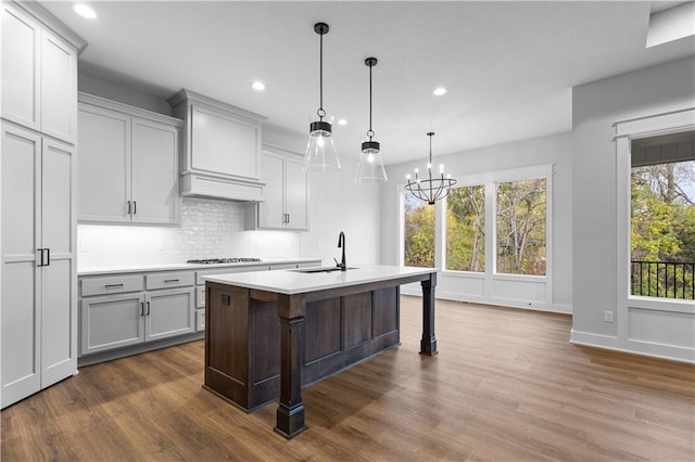 kitchen featuring dark wood-type flooring, a wealth of natural light, and a center island with sink