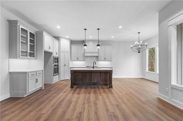 kitchen featuring pendant lighting, sink, hardwood / wood-style flooring, and a center island with sink