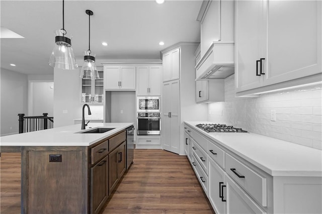 kitchen with stainless steel appliances, white cabinetry, sink, an island with sink, and dark wood-type flooring