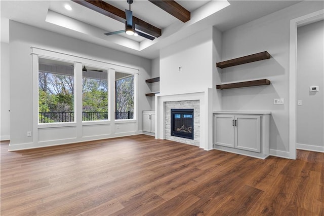 unfurnished living room featuring beamed ceiling, hardwood / wood-style flooring, ceiling fan, and a fireplace